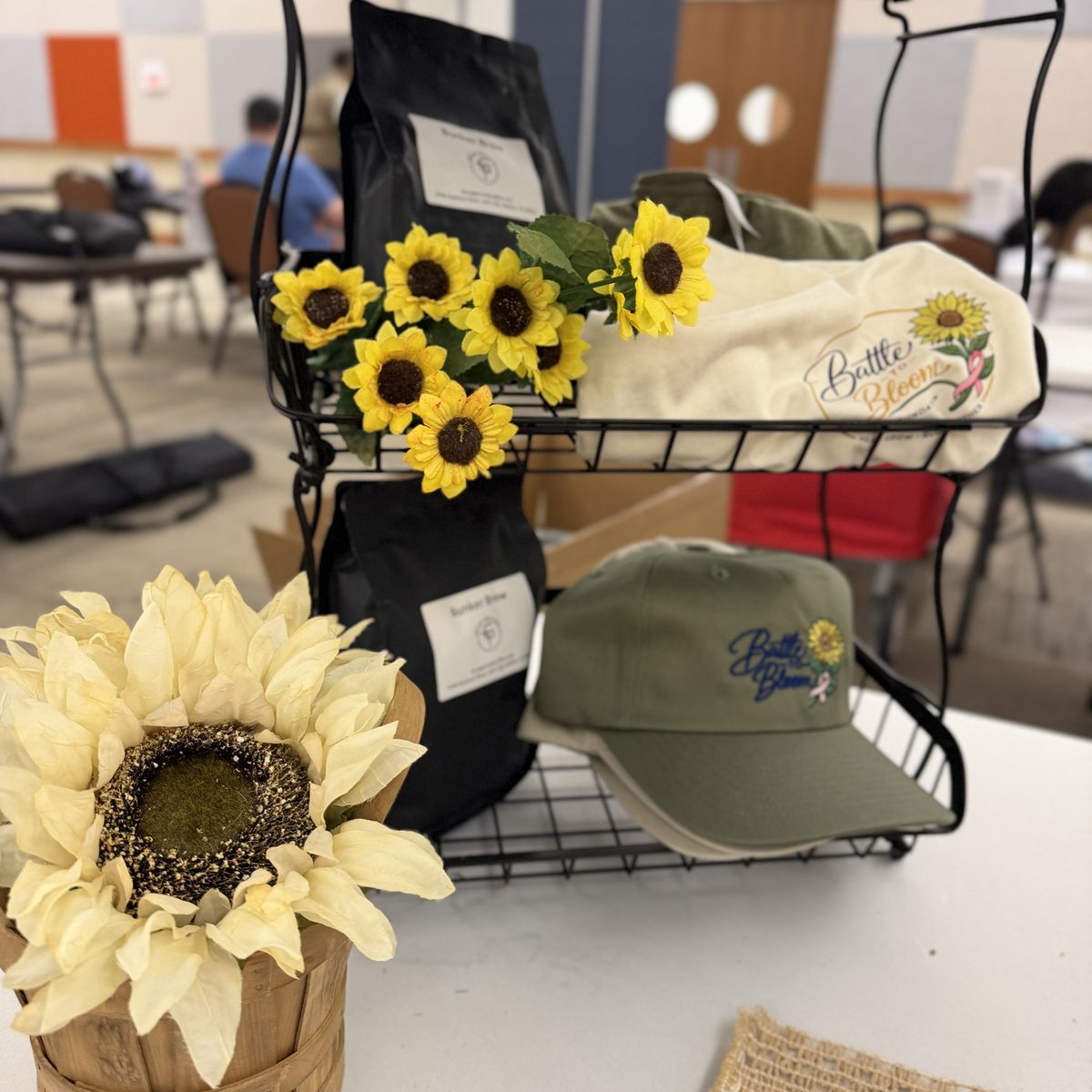 Battle to Bloom and Bunker Brew merch display with sunflowers